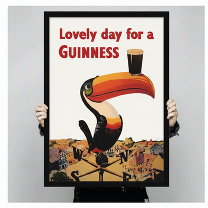 Hand-held black framed print of the iconic Guinness toucan vintage poster with "Lovely Day for a Guinness" text, showing print size and frame quality