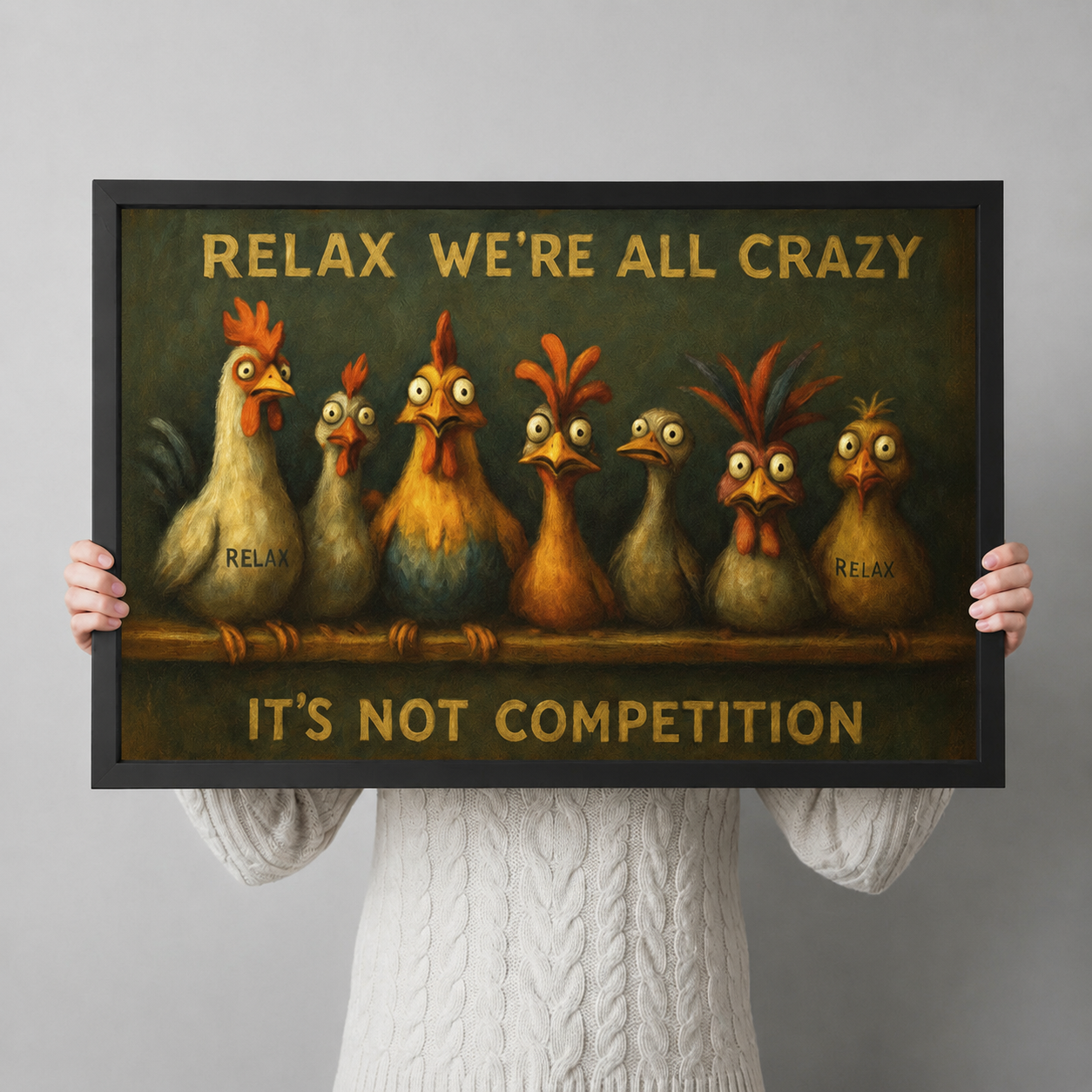 Close-up of black framed "Relax We're All Crazy It's Not Competition" funny chicken canvas print held by two hands against neutral background