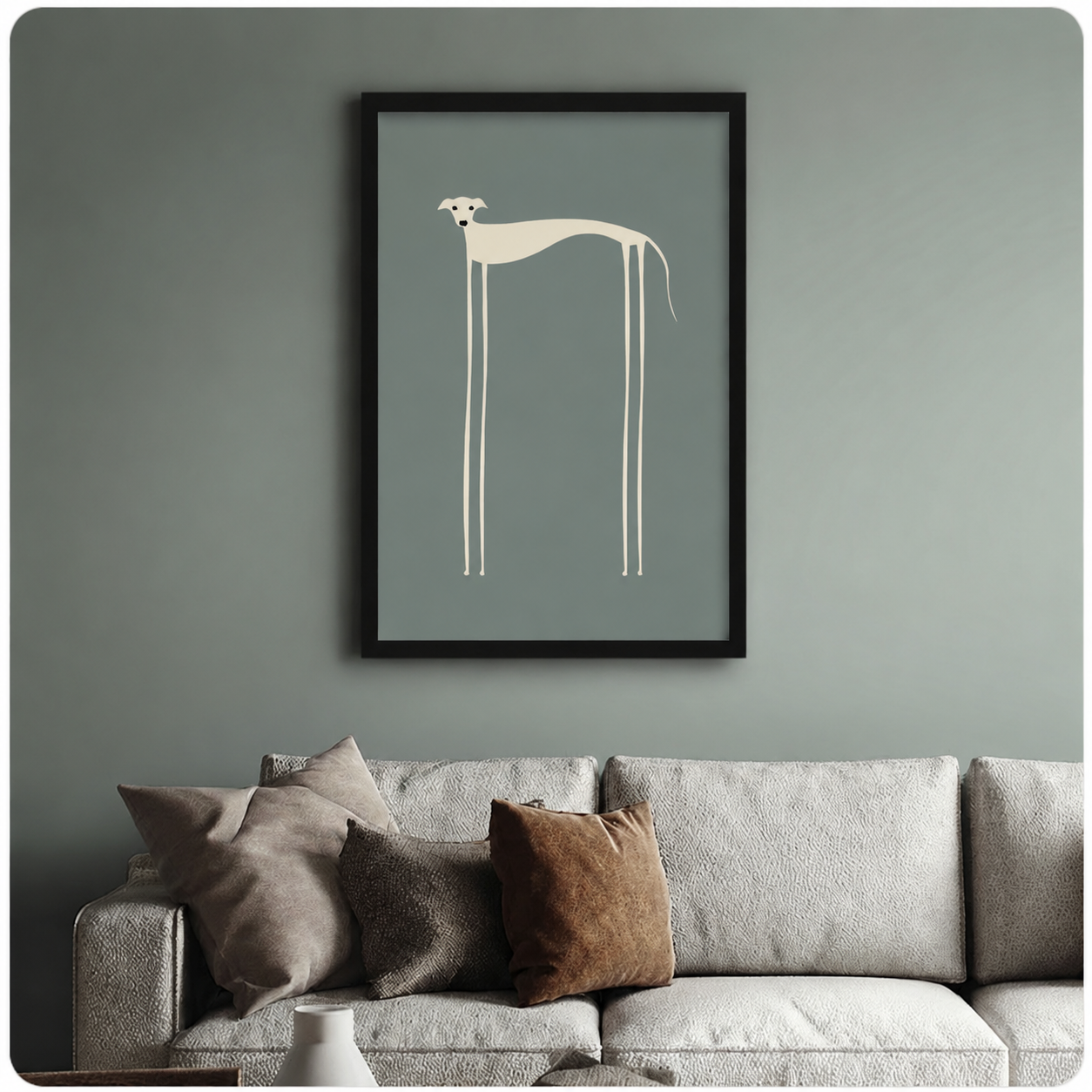 Black framed abstract dog wall art print showing a stylised greyhound silhouette in cream on a dusty blue-green background, mounted above a neutral linen sofa against a sage green wall