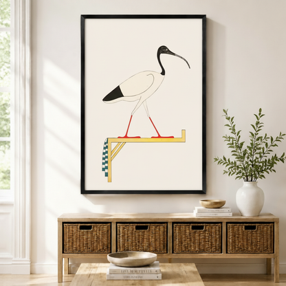  Framed ancient Egyptian sacred ibis standing on a golden perch illustration with red legs and checkered detail displayed above a wicker console in a bright modern entryway
