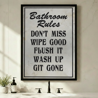 Framed funny Bathroom Rules quote canvas wall art with vintage distressed white texture and bold black typography reading Don't Miss Wipe Good Flush It Wash Up Git Gone displayed above a bathroom sink with green plants