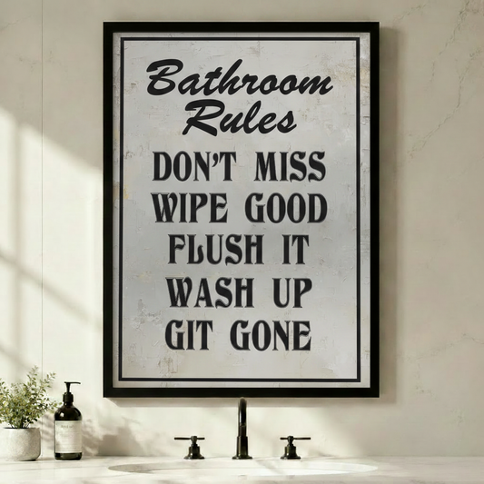 Framed funny Bathroom Rules quote canvas wall art with vintage distressed white texture and bold black typography reading Don't Miss Wipe Good Flush It Wash Up Git Gone displayed above a bathroom sink with green plants