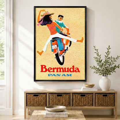 Framed canvas print of a vintage Bermuda Pan Am travel poster featuring a couple riding a moped, displayed above a rattan storage console in a bright modern entryway