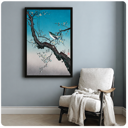 Bird perched on plum blossom branch framed poster beside accent chair on blue-grey wall, serene Japanese nature art print for modern home