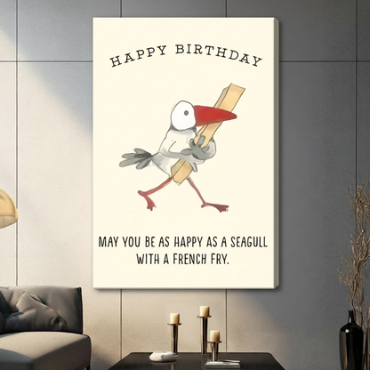 Gallery-wrapped stretched canvas of a chubby cartoon seagull holding a french fry with Happy Birthday and may you be as happy as a seagull with a french fry quote, funny illustrated bird print on off-white background, hung above a dark sideboard with candlesticks against a gray paneled wall