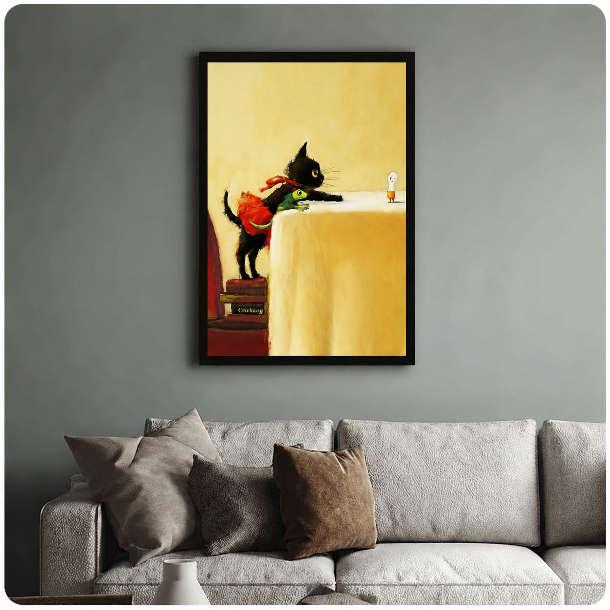 Black cat carrying frog illustration in black frame above grey sofa, warm yellow toned living room wall art