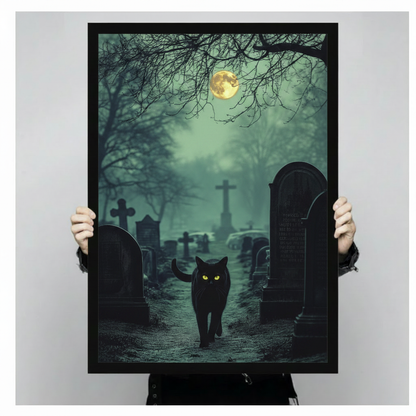 Dramatic gothic art print of a black cat with intense neon green glowing eyes advancing through a fog-filled cemetery at night surrounded by dark stone cross and arched tombstones with twisted bare tree branches overhead and a glowing full moon partially obscured by teal green mist gothic halloween cat graveyard wall art framed wall art print held up for size reference against a light gray neutral background