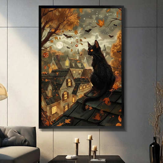 Orange-eyed black cat sitting on a rooftop overlooking a glowing Halloween village with Victorian houses jack-o-lantern string lights flying bats autumn leaves and a full moon in a smoky starlit sky whimsical Halloween cat wall art framed print in a living room with blue gray tiled wall dark sofa candle holders and black vase