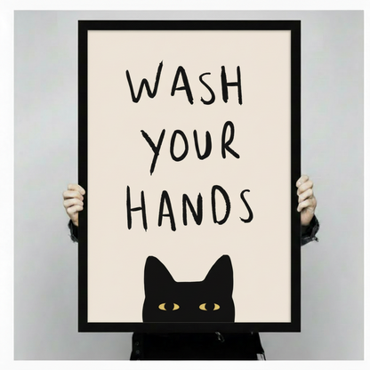 Hands holding large framed black cat wash your hands canvas print - full artwork view of peekaboo cat with yellow eyes and hand-lettered quote