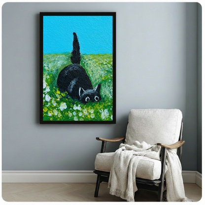 Funny black cat wall art print in black frame hanging above armchair — playful cat in flower field canvas