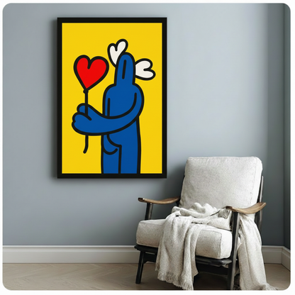 Framed canvas print of blue figure with red heart balloon hung above armchair in cozy home reading nook