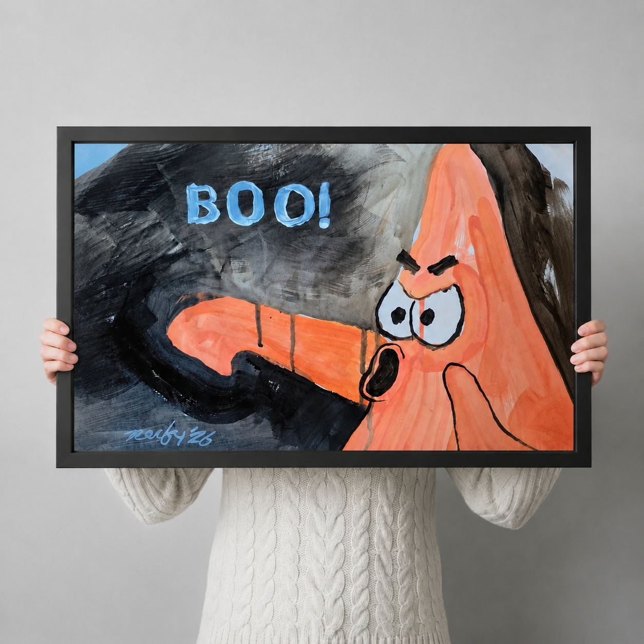 Person holding black framed horizontal art print of angry cartoon monster with BOO text, fun pop art wall decor