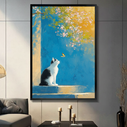 Cat and butterfly impressionist canvas wall art in black frame on gray wall above white armchair