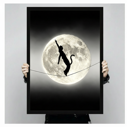 Black and white surreal photograph of a cat-girl silhouette with cat ears and tail balancing on a tightrope in front of a glowing full moon on a dark night sky wall art framed print held against light gray background