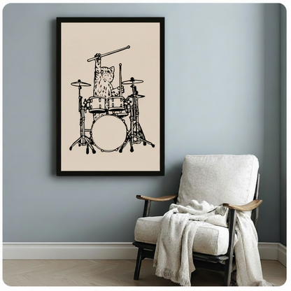 Black framed cat drummer poster print hanging on light blue-gray wall beside a cozy white armchair