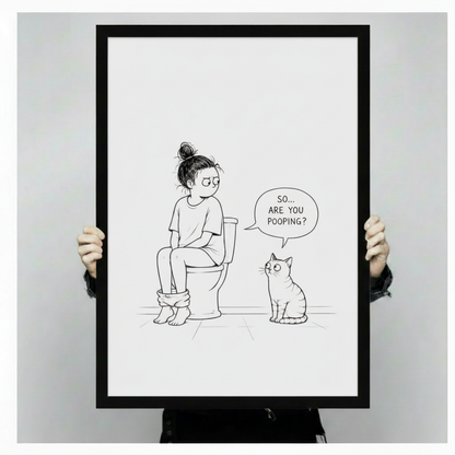 Funny cat bathroom wall art in black frame showing a girl on a toilet and a curious cat, styled in an elegant bathroom with marble countertop and gold brass fixtures