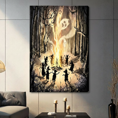 Gallery wrap stretched canvas of nine black cat silhouettes standing on hind legs with arms raised dancing around a blazing campfire as ghostly white faces emerge from the flames surrounded by gnarled bare trees and scattered wildflowers gothic Halloween dark fantasy illustration on warm golden brown smoky background hung frameless on a gray wall above a dark sofa