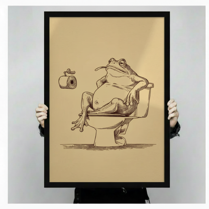 Person holding a large framed canvas of a chubby frog lounging on a toilet with a toilet paper roll, showcasing the warm tan background, detailed sketch linework, and black frame