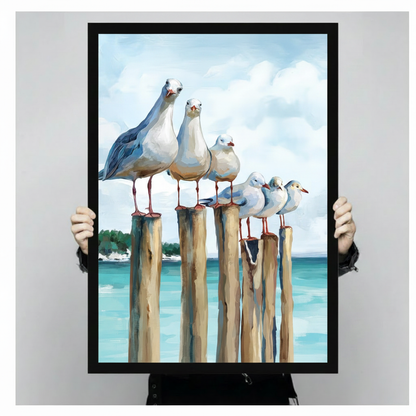 Person holding a large black framed coastal seagull pier canvas art print showing print size scale and detailed oil painting texture of five white seagulls on weathered wooden posts with turquoise ocean background
