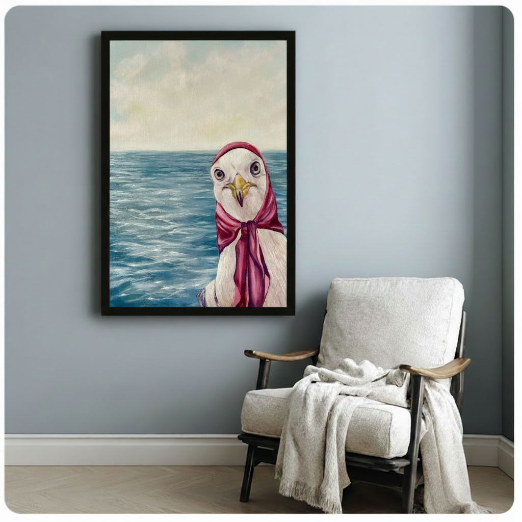 Framed oil-style canvas print of a quirky seagull wearing a red headscarf by the sea, hung on a light blue-grey wall beside a cozy white linen armchair in a Scandinavian reading nook