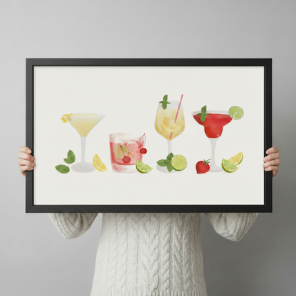 Person holding a black-framed cocktail art print showcasing margarita, highball, spritz, and frozen drink illustrations with fresh fruit