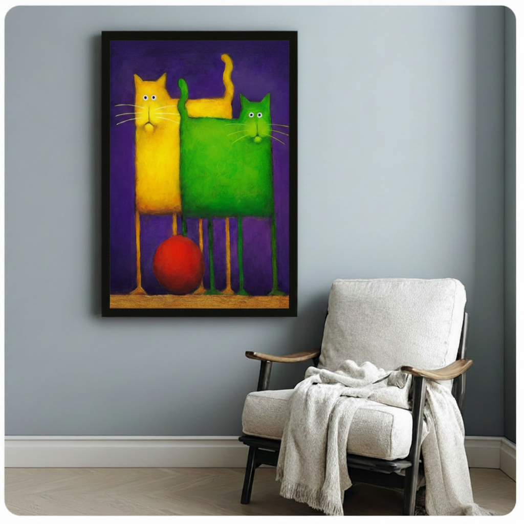 Black framed whimsical yellow and green abstract cat pair canvas art with bold saturated colors and a striking red ball on a deep purple background, displayed on a soft blue-gray wall beside a white wooden folding armchair draped with a cream linen throw blanket