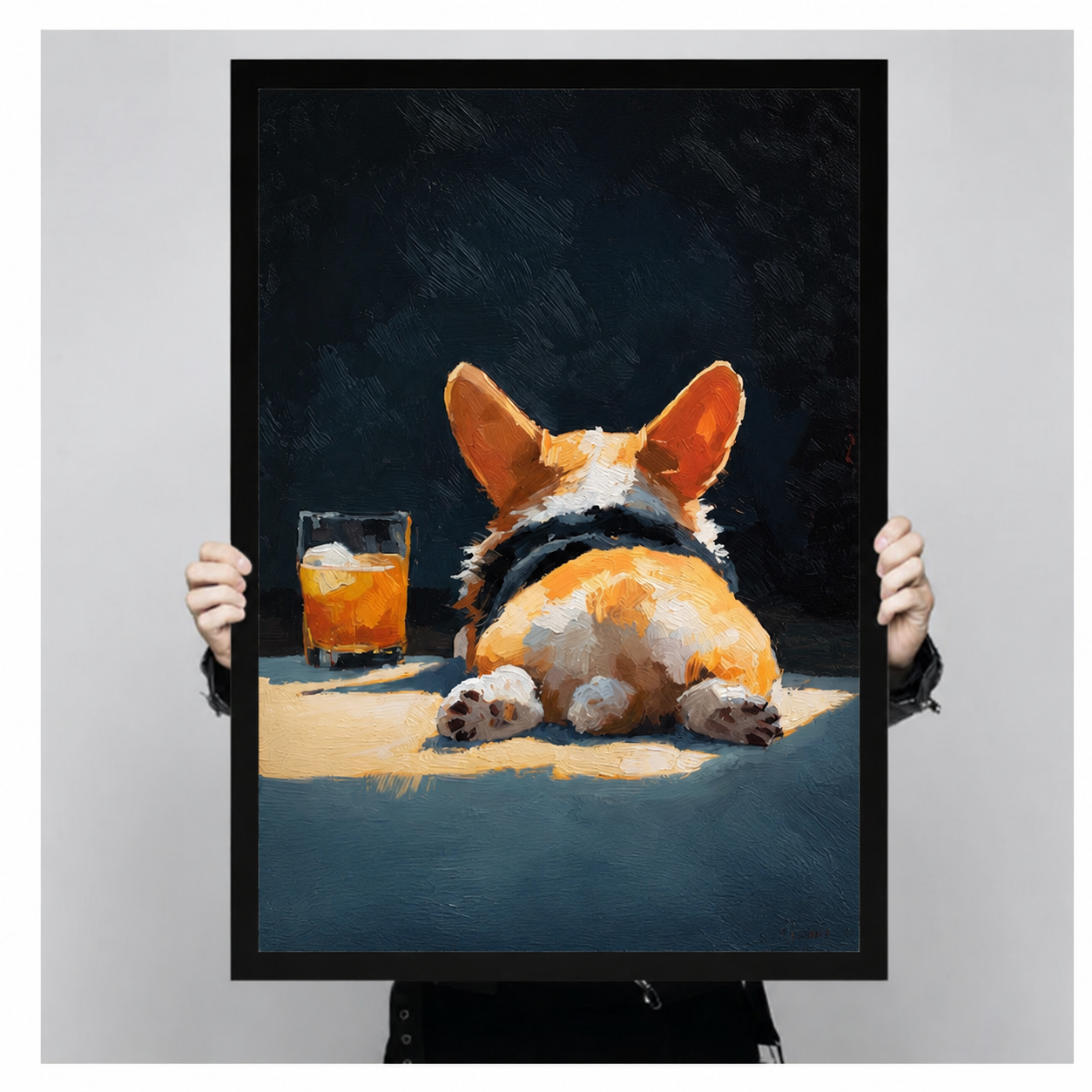 Close-up of a black-framed corgi butt and whiskey glass art print being held by two hands, showing rich oil painting texture and warm amber tones