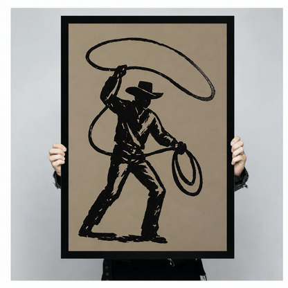 Person holding black-framed cowboy wall art featuring a sweeping lasso and bold silhouette on a taupe background.⠋