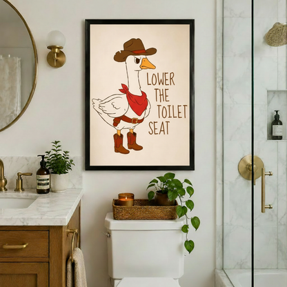 Funny cartoon illustration of a grumpy white goose in a brown cowboy hat red bandana and cowboy boots with the text Lower The Toilet Seat on a cream background funny bathroom wall art framed print above toilet in marble bathroom with gold fixtures and glass shower