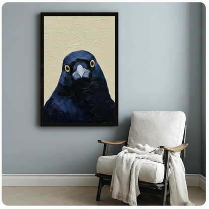 Moody dark blue crow portrait framed poster beside cozy armchair, expressive bird face with golden eyes on beige textured background, black frame wall art