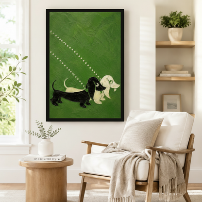 Framed wall art print featuring two whimsical dachshunds on olive green painted canvas, styled beside a linen armchair and round side table