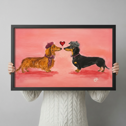 Person holding a framed dachshund couple art print showing size reference against a grey background