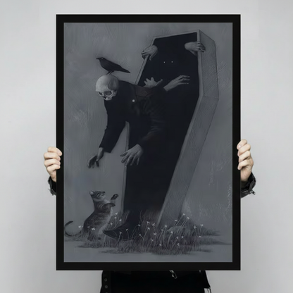 Hand-held display of a black-framed canvas art print featuring a dramatic dark gothic skeleton emerging from a coffin with a raven on its skull, reaching toward a small animal among wildflowers on a charcoal grey background