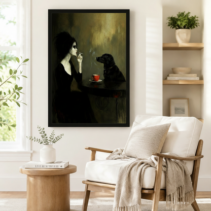 Bold framed dark art print of a gothic woman in black dress gazing at a black labrador across a small table with a red coffee cup in a moody olive-toned interior, styled beside a linen armchair in a bright Scandinavian reading corner
