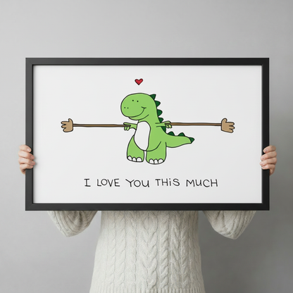 Person in white knit sweater holding a large black framed cute dinosaur love quote canvas art print against a neutral gray background, horizontal product size reference display