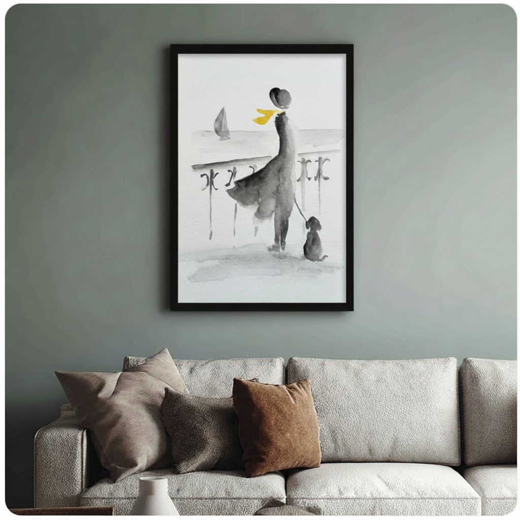 Framed watercolor art print of a woman in flowing dress with dog by the sea, hung above a neutral linen sofa on a sage green wall