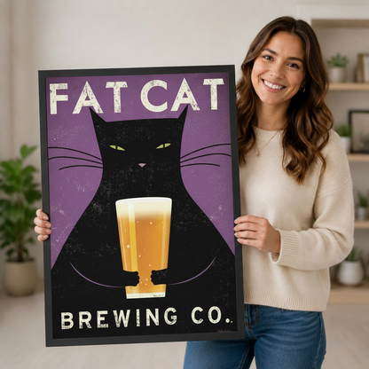 Smiling woman holding large black framed Fat Cat Brewing Co vintage black cat beer wall art print on purple background in bright home interior lifestyle photo