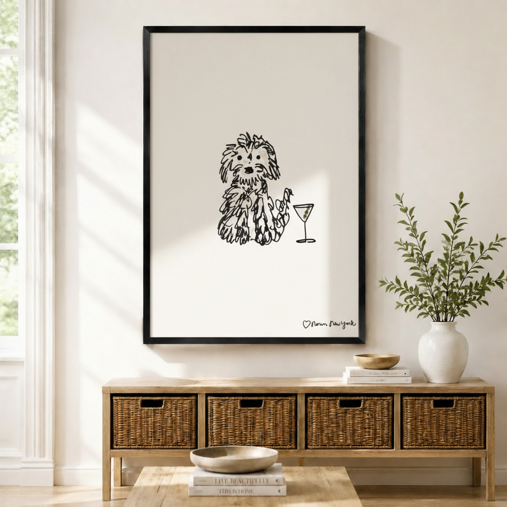Whimsical fluffy dog with martini glass line art print in black frame above wicker console table in bright neutral entryway
