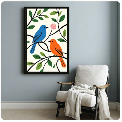 Framed folk-art style canvas print of a blue bird and orange bird on leafy branches with a pink bloom, hung above a cozy armchair in a light grey living space