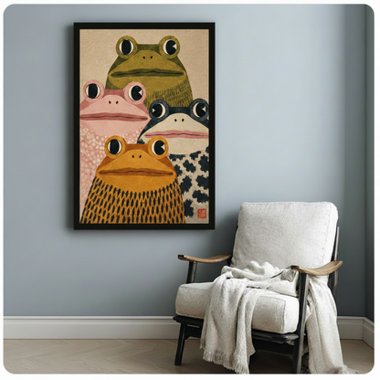 Japanese folk art style illustration of four stout frogs in a close group portrait featuring olive green pink black-spotted and golden orange frogs with wide round eyes and patterned skin on a sandy beige background with red stamp accent funny frog wall art framed print beside a white lounge chair with throw blanket against a blue-gray wall