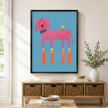 Funky pink dog wearing orange star rain boots with yellow bird on back black framed canvas art in sky blue above a rattan sideboard with wicker baskets, stacked books, and a white ceramic vase in a Scandinavian living room