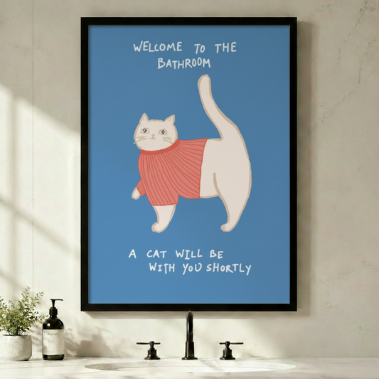 Framed funny whimsical illustration chubby white cat wearing pink ribbed turtleneck sweater with tail raised high and bold handwritten text Welcome To The Bathroom A Cat Will Be With You Shortly on steel blue background canvas print on light grey wall above black faucet bathroom sink with soap dispenser and small green plant - humorous bathroom cat sweater welcome wall art for contemporary powder room decor