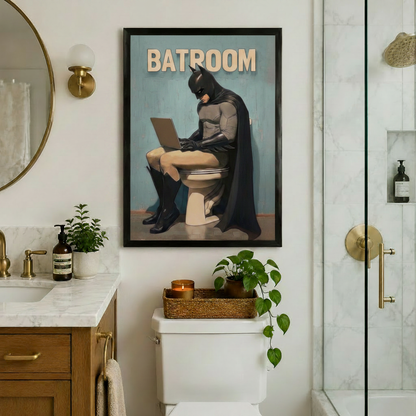 Comic Batman Batroom framed poster on a white marble bathroom wall beside a round mirror with gold sconce, above a toilet with candle tray and trailing green plant next to a glass shower