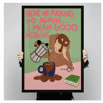 Person holding a large vertical black framed funny dachshund pouring coffee canvas art print showing a drowsy brown wiener dog spilling coffee from a moka pot with a sarcastic here we go again I mean good morning quote in pink text on a green and pink background against a light gray studio backdrop