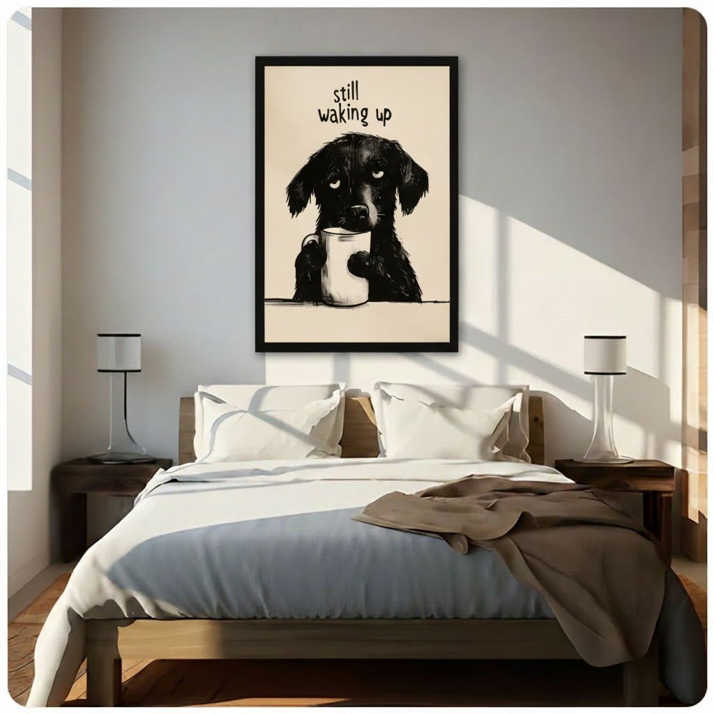 Black framed funny illustration sleepy black dog holding white coffee cup "Still Waking Up" quote canvas art on warm beige background above a bed with white linen bedding, a taupe throw blanket, dark wood nightstands, and white cylindrical table lamps in a sunlit modern bedroom