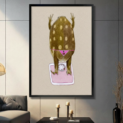 Funny frog wall art print showing a chubby spotted frog in pink cherry bikini standing on a pink bathroom scale, displayed in black frame on dark gray wall in modern living room