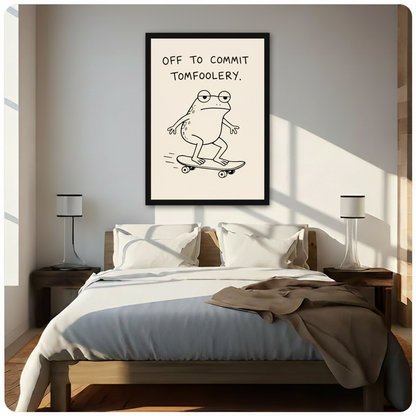 Framed minimalist line drawing of a chubby frog with round glasses riding a skateboard with the witty quote Off To Commit Tomfoolery in bold black handwritten text on a cream background canvas wall art hung above a dark walnut bed with white bedding in a sunlit bedroom