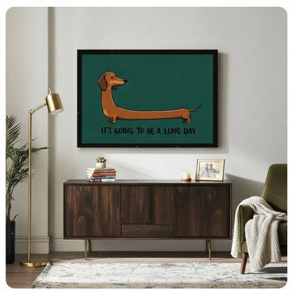 Black framed cartoon long dachshund "It's Going to Be a Long Day" horizontal wall art in teal green above a dark walnut sideboard with stacked books and a succulent, beside a brass floor lamp and olive green armchair with a knit throw blanket in a modern living room