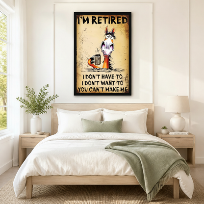 Black framed retro grunge funny retired horse coffee canvas art with bold I'm Retired text above a wide-eyed bug-eyed cartoon horse with a wild mane clutching a steaming metal coffee mug and the humorous quote I Don't Have To I Don't Want To You Can't Make Me on a distressed aged yellow-brown rust-textured background, hung above a light wood bed frame in a bright Scandinavian bedroom with crisp white linen bedding, a sage green accent pillow and throw blanket, a light wood nightstand, a white round ceramic 