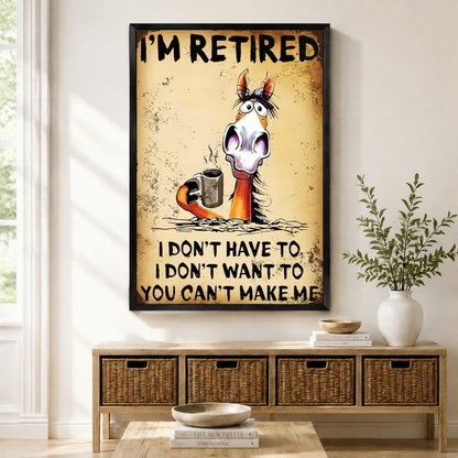 Black framed retro grunge funny retired horse coffee canvas art with bold I'm Retired lettering above a startled wide-eyed cartoon horse with disheveled mane holding a steaming metal coffee cup and the cheeky retirement quote I Don't Have To I Don't Want To You Can't Make Me on a heavily distressed aged amber rust-textured background, displayed on a white wall above a light wood rattan basket storage console with a white ceramic bowl, stacked books, and a white vase of greenery in a bright sunlit entryway